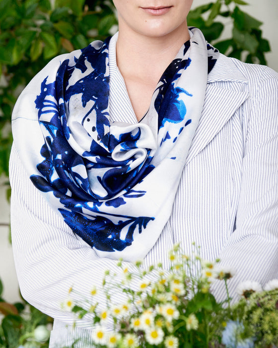 Kvadratisk silketørklæde med blå blomster, blomster silketørklæde, Silketørklæde med mørkeblå blomster, Silketørklæde med vilde mørkeblå blomster, silketørklæde med håndmalet look i blå blomster.   Silketørklæde kvadratisk 65 x 65 cm, Silketørklæde i 100 % ren silke, silketørklæde i ægte silke twill, silketørklæde med design af Susanne Schjerning, silketørklæde med rullede kanter. Giv et silketørklæde i gave. Bæredygtigt silketørklæde i dansk design.